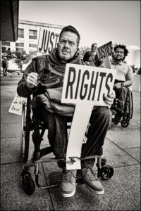 ADAPTer in wheelchair holding a sign saying “Rights”.